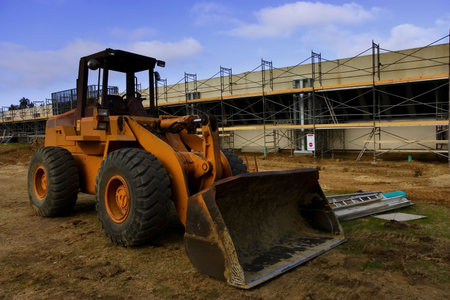 Earth mover in front of scaffolding for a new parking lot under construction