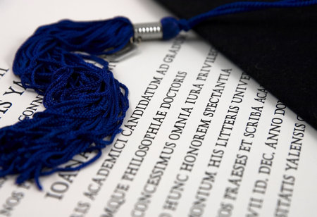 Black graduation hat with tassel over diploma in Latinの写真素材