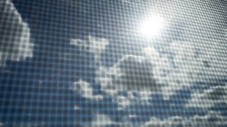 Closeup of mosquito wire screen with sun ray on blue sky and white clouds in backgroundの写真素材