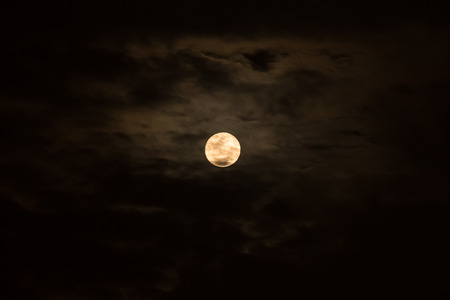 Full moon in the dark sky among the clouds, natural abstract black background. Moonlight flowing from the dark sky.の写真素材