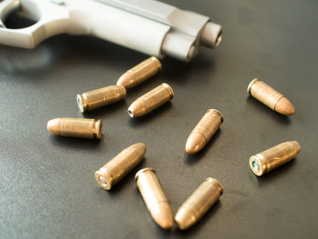 11mm bullets and short gun on black background. (selective focus)