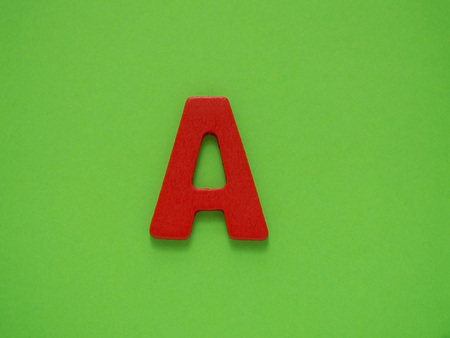 Capital letter A. Red letter A from wood on green background. Alphabet.の写真素材