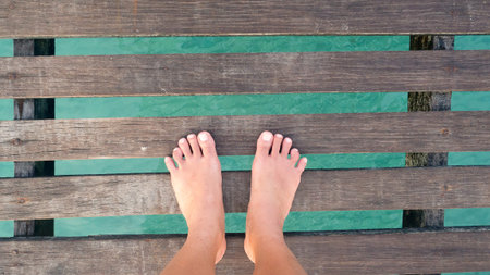 Woman feet stand on wooden bridge over sea. Vacation holiday enjoying sun on sunny summer day...