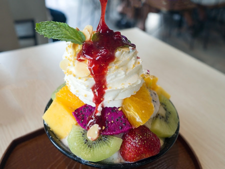 Bingsu fruits berry. Bingsu is local Korean shaved ice dessert serve with toppings such as chopped fruit, mango, orange, kiwi, strawberry, dragon fruit and berry syrup.の写真素材