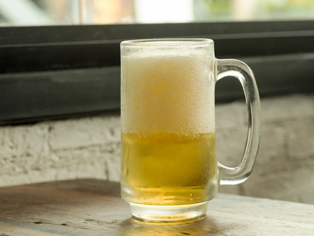 Glass of frosty beer on table in restaurant.の写真素材