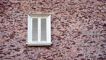 Brown and red brick wall with vintage white window.