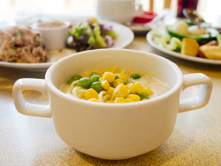 Cream soup with corn and green pea in white bowlの写真素材