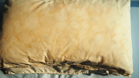 Dirty pillow with pale yellow and brown color from saliva stain on bed.の写真素材
