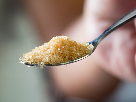 Brown sugar in spoon in hand holding.の写真素材