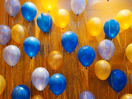 Blue, orange, yellow and white balloons decoration on golden wall.の写真素材