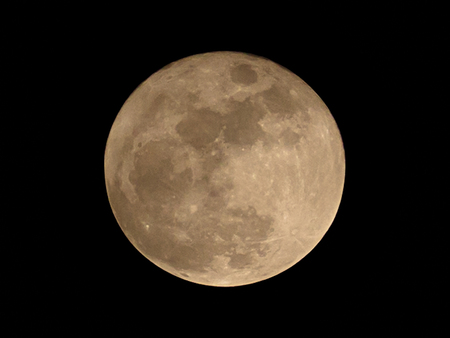 Super full moon over dark black sky at nightの写真素材