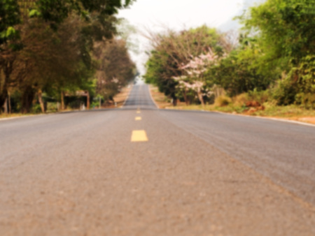 Defocus and blur image of long outback road with trees at wayside. Natural background.の写真素材