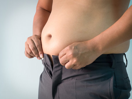 Overweight man trying to fasten too small pants, fat man with a big belly. Diet concept. Weight lose...