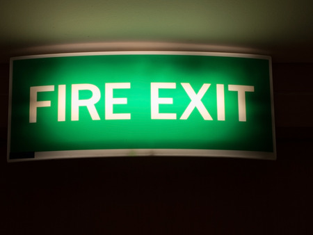 Fire exit sign. Light green emergency fire exit sign in the office/hotel shows people way out.の写真素材