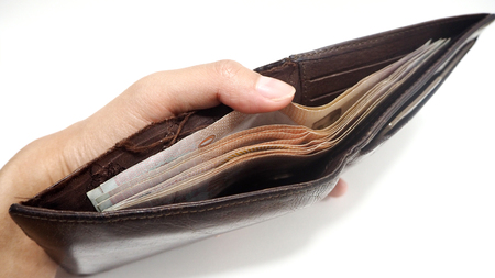 Woman hand open old brown leather wallet with has Thai banknotes inside. Money expense and saving concept.の写真素材
