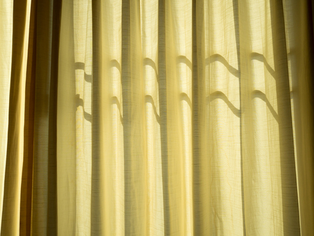 Soft yellow linen texture blinds curtains with sunlight through the windows. sun-blind.の写真素材