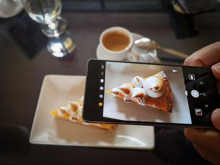 Lemon curd tart cake. Hand using camera in smart phone take photo of lemon curd tart before eat.