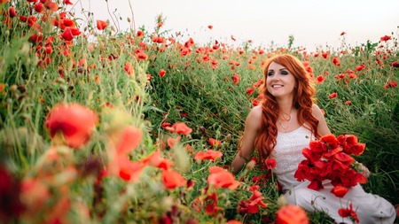 beautiful young woman in poppy field holding a bouquet of poppies, summerの写真素材