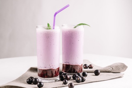 cold milkshake with a black currant on a white background, close-upの写真素材