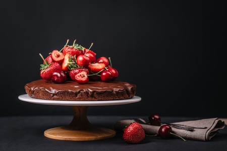 Tuscan chocolate cake with strawberries and cherries on dark backgroundの写真素材