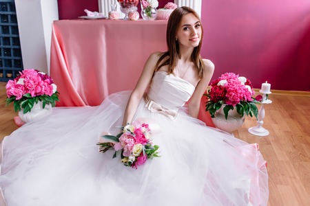 young beautiful bride with a bouquet of pink peonyの写真素材