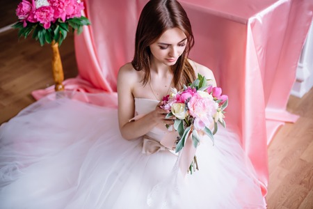 young beautiful bride with a bouquet of pink peonyの写真素材