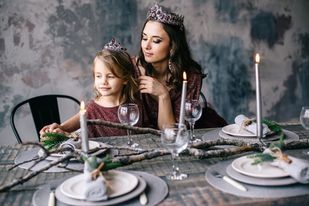 mother and daughter in the image of the queen and princess dresses in the colors of Marsala the Christmas tableの写真素材