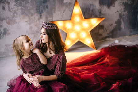 mother and daughter in the image of the queen and princess dresses in the colors of Marsala with a...