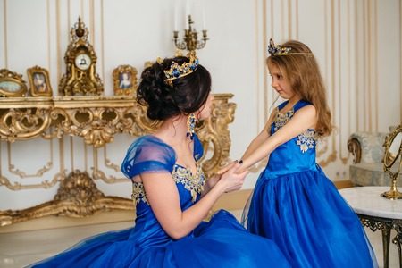 Beautiful princess mother and daughter in a gold crown and luxurious blue dressesの写真素材