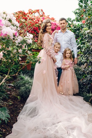 Young happy family - mom, dad, daughter and son, in a blooming spring gardenの写真素材