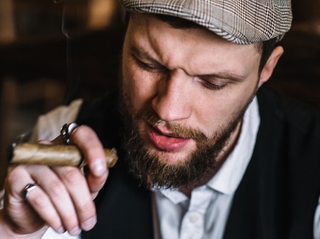 A young bearded man smoking a cigar in a pubの写真素材