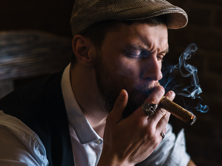 A young bearded man smoking a cigar in a pubの写真素材