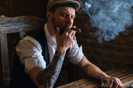A young bearded man smoking a cigar in a pubの写真素材