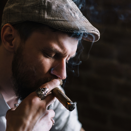 A young bearded man smoking a cigar in a pubの写真素材