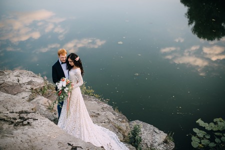 Happy newlyweds standing and smiling on the river bankの写真素材