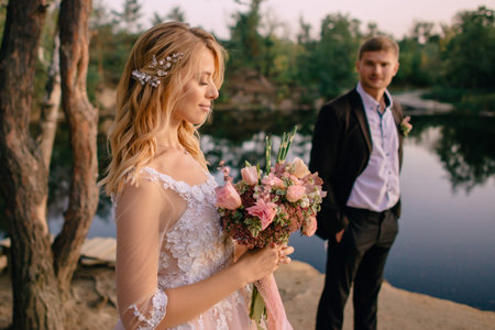 happy newlyweds standing against nature background at sunsetの写真素材