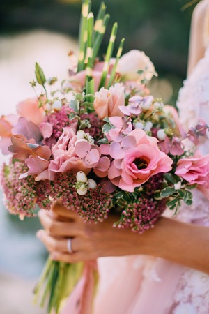 wedding bouquet in the hands of the bride against nature background, close-upの写真素材