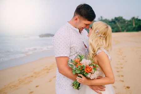 newlyweds standing and hugging on tropical beachの写真素材