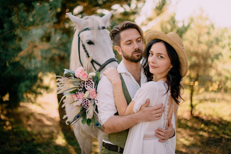 newlyweds dressed boho style standing near horseの写真素材