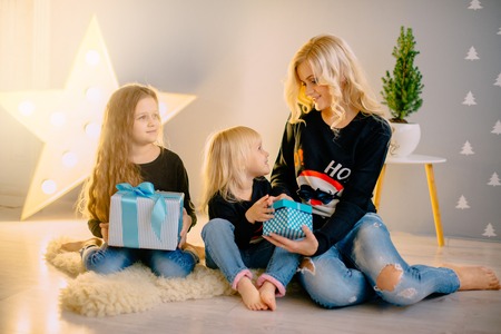 mother and two little daughters considering Christmas presents in bright roomの写真素材