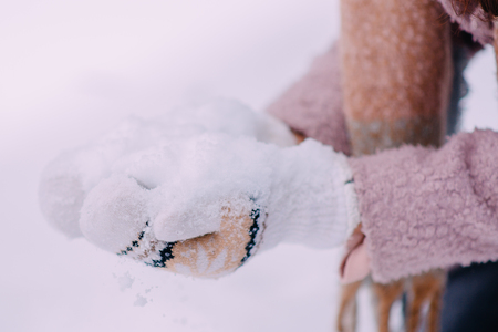 womens hands in mittens make snowballs, close-upの写真素材