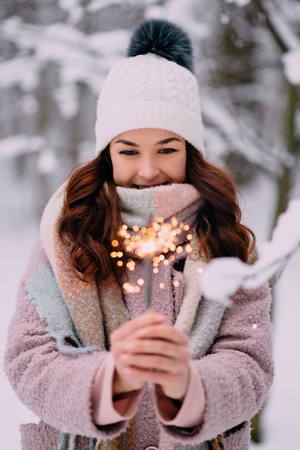 joyful woman holding burning sparklers in winter forestの写真素材