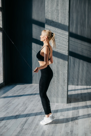 Young woman is jumping with rope in sports studioの写真素材