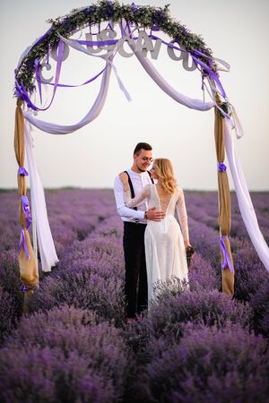 Young happy bride and groom hugging in flowering lavender fieldの写真素材