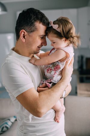 Young father holds on hands little daughter at home, close-upの写真素材