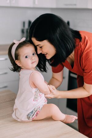 Young happy mother looks at her baby at homeの写真素材
