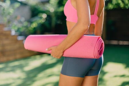 Young woman holds yoga mat in hand, close-upの写真素材