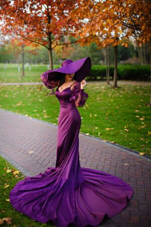 Young woman in luxurious dress is standing in autumn parkの写真素材