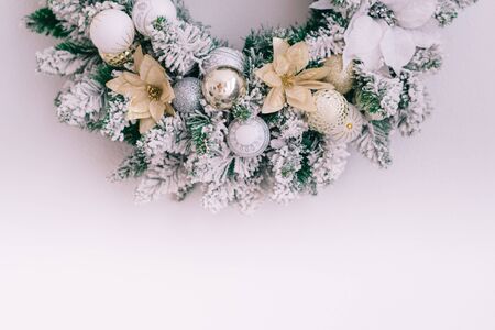 Close-up of a snowy christmas wreath on a white wall with place for textの写真素材