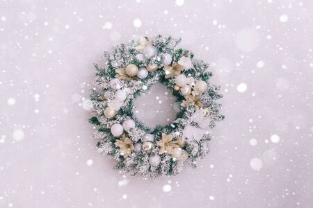 Close-up of a snowy christmas wreath on a white wall with place for textの写真素材
